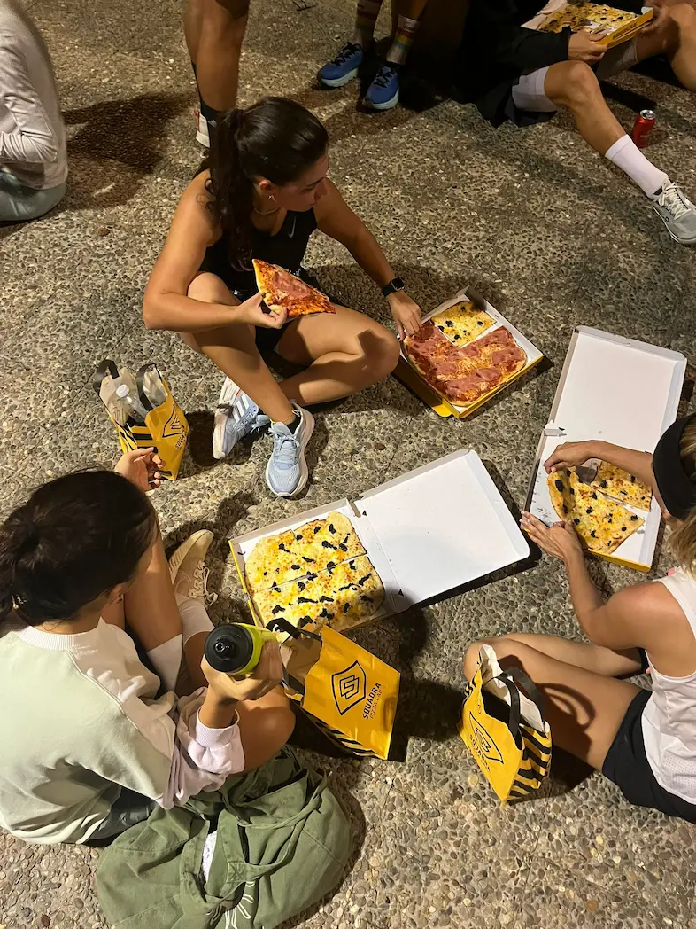 Tres chicas comiendo pizza en Squadra Social Run